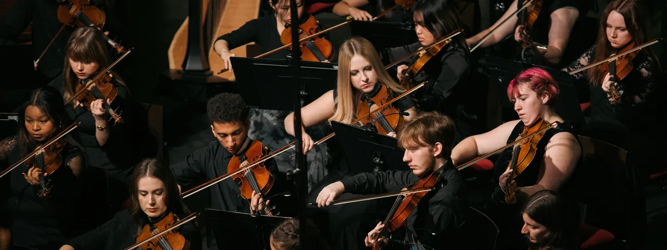 Students play string instruments.
