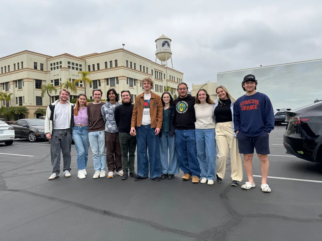 A group of students pose and smile outside a movie studio.