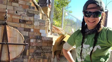 A student stands next to a ceramics kiln.