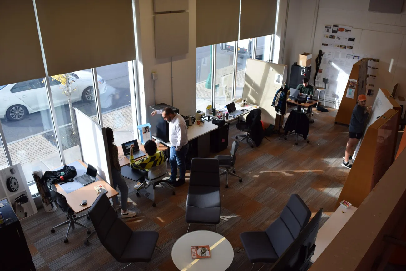 A view looking down at a design studio where people are working at tables.