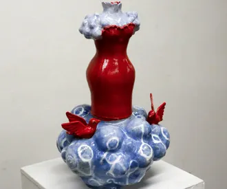 A sculpture of a human outline/red dress on top of a blue base.