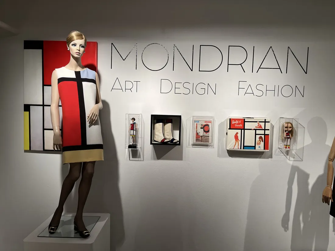 A mannequin wearing a dress with color blocks stands in a gallery next to the sign Mondrian: Art Design Fashion.