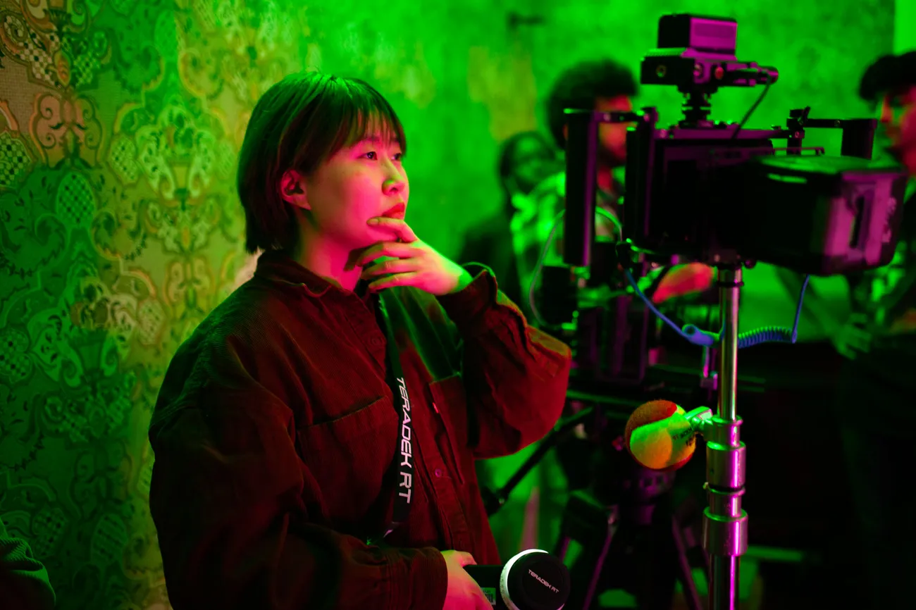 A student looks through a film camera on a film set.