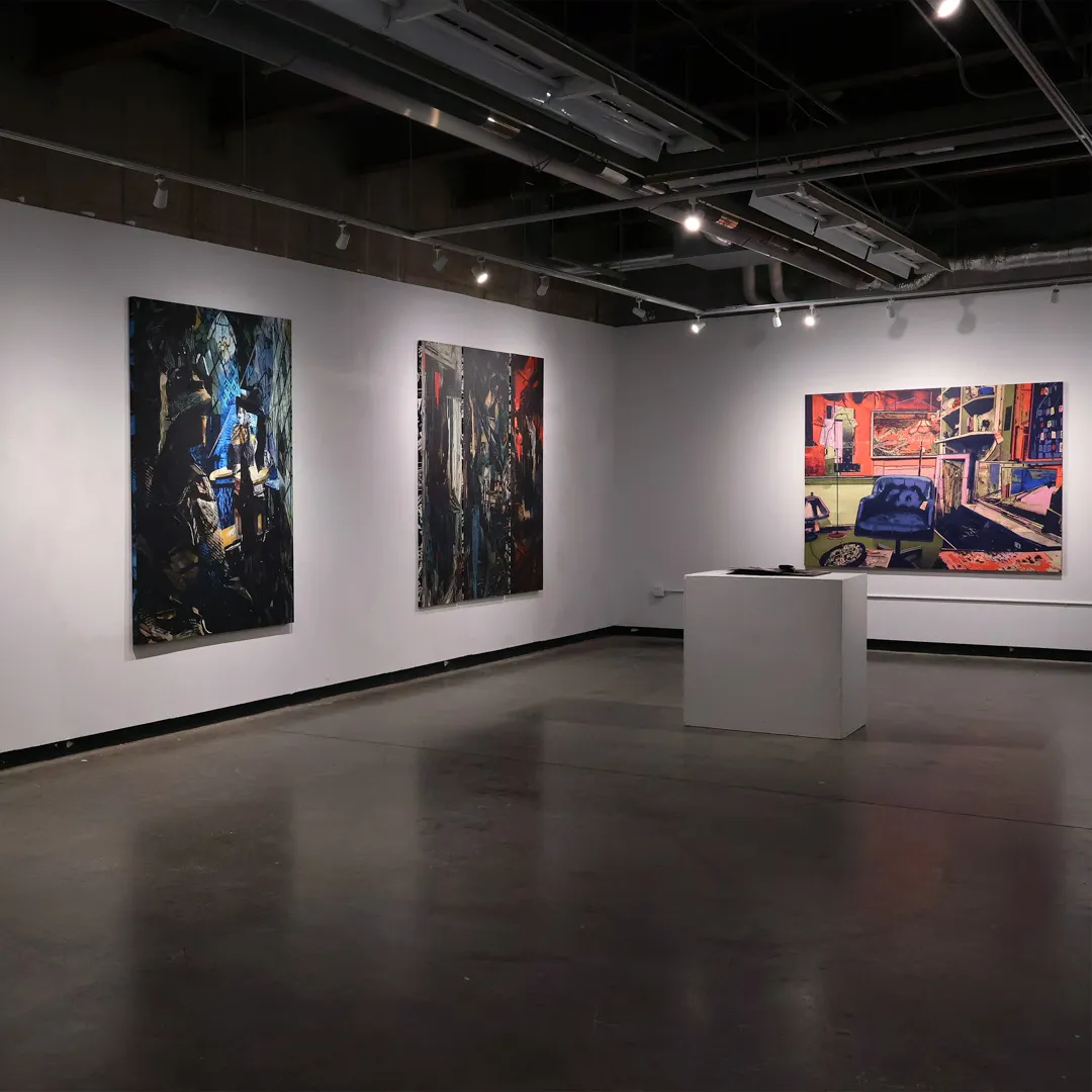 A gallery with three pieces of art hanging on the walls.