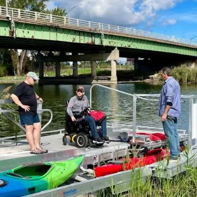 Three individuals by a kayak.