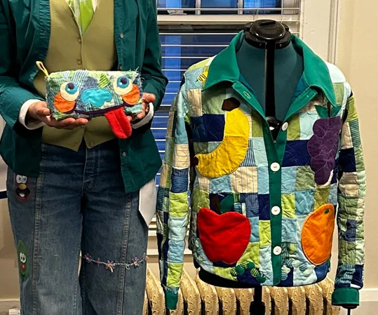A person stands beside a fabric jacket, holding a purse.