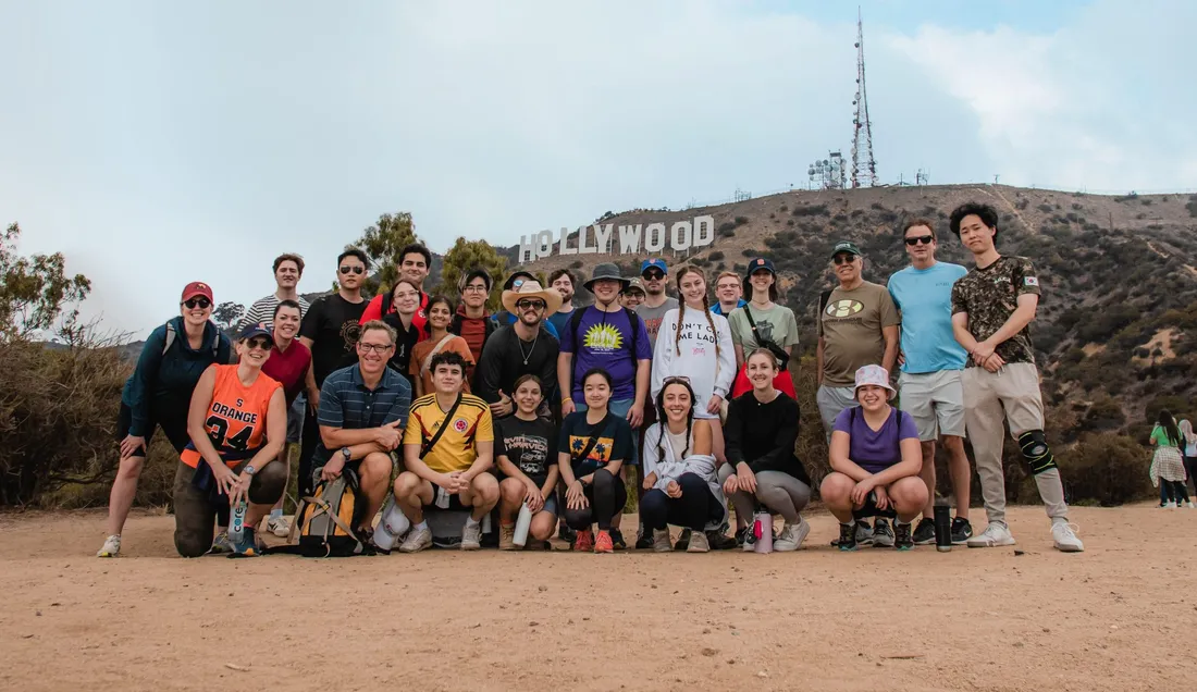 A group of students and faculty pose in front of the Hollywood sign.