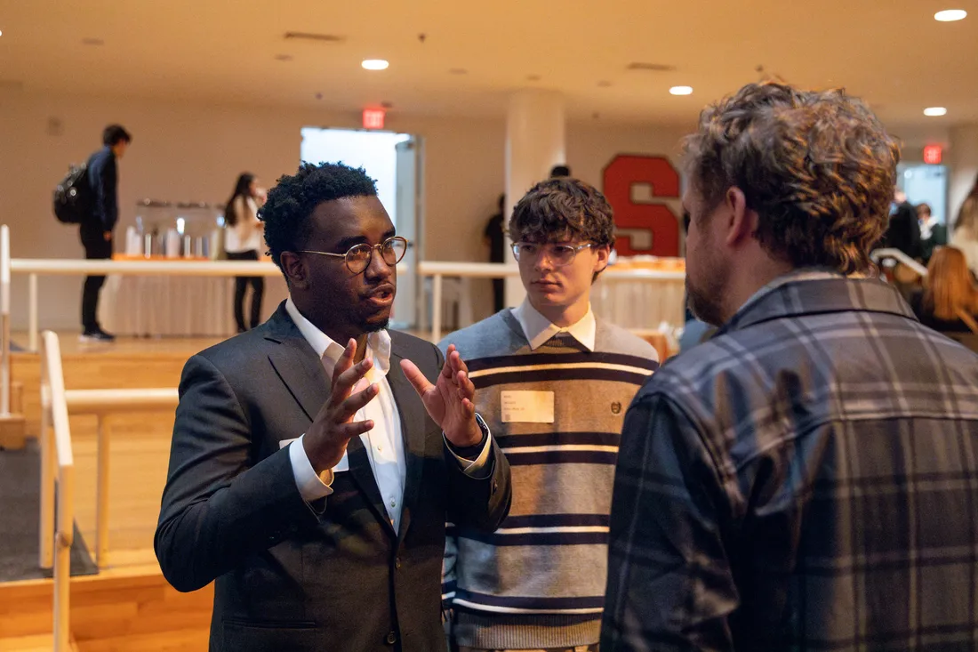 A student speaks to another person as another student looks on.