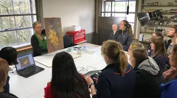 Students gather around a table with items.