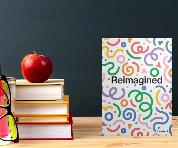 A book with the title Reimagined. On the side is a stack of books with an apple on top.