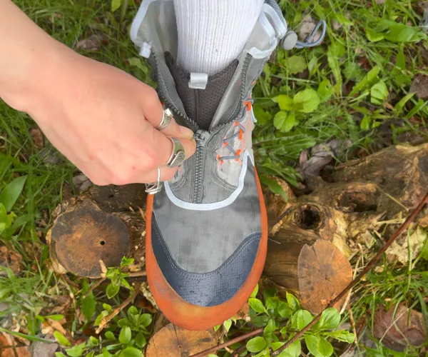 A person zips up a shoe.