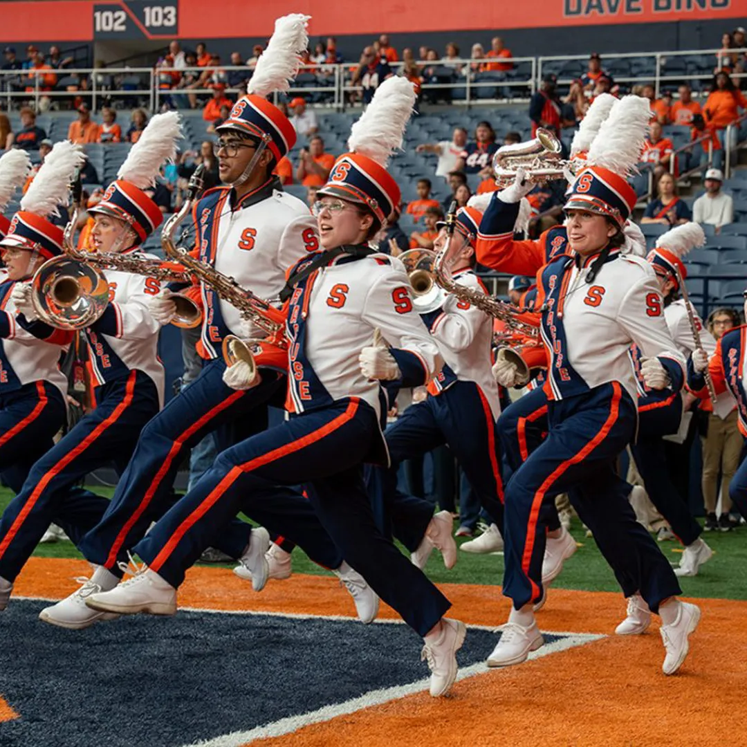 Members of the Syracuse University Marching Band run onto the field.