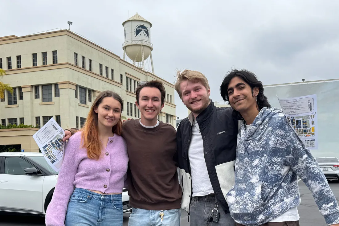 A group of students pose and smile in a parking lot outside Paramount Studios.