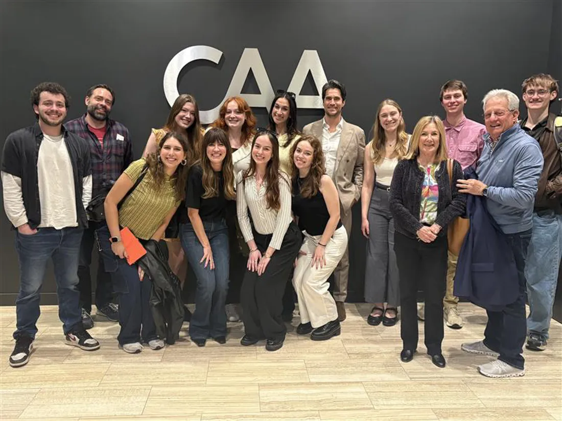 Individuals participating in Gilbert Week pose in front of the Creative Artists Agency logo.