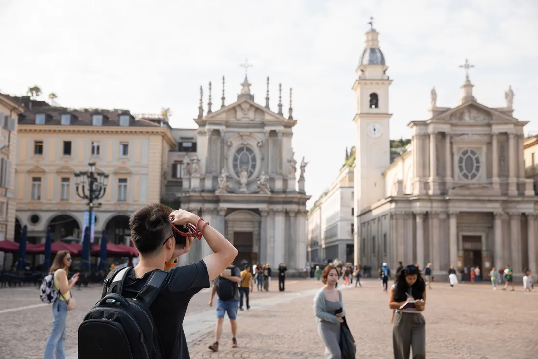 A person takes a photo of a historic building in Torino, Italy.
