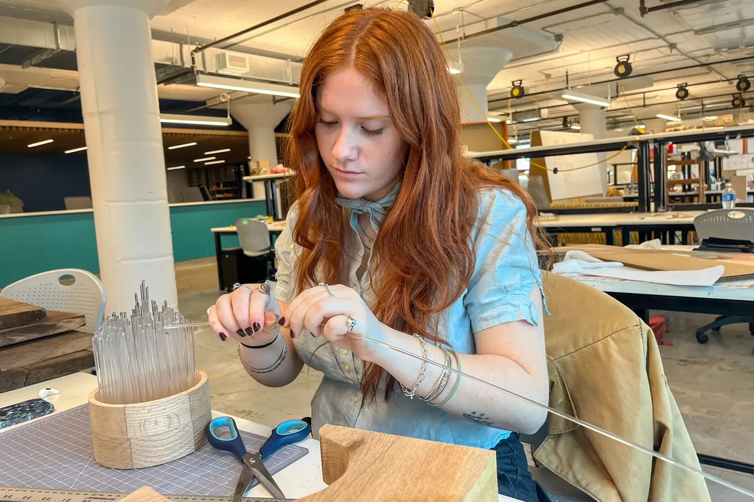 A student works on a project with wood and a plastic material.