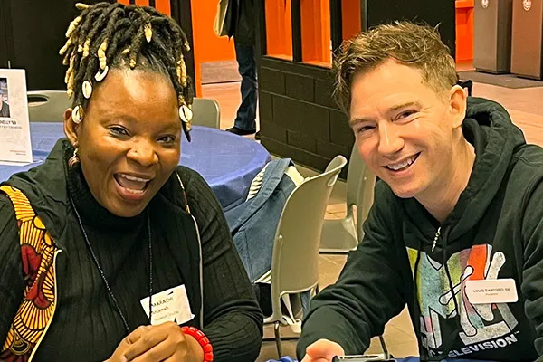 A student and alumnus sit together and smile.