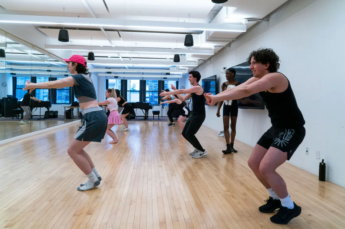 A group of students take a movement class in a dance studio.