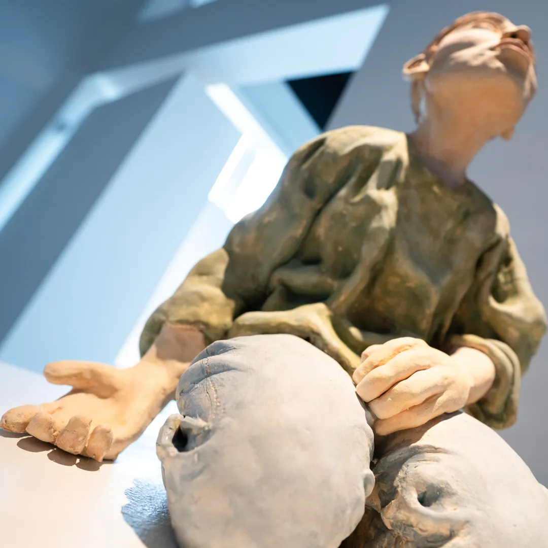 Sculpture of a person kneeling with one arm outstretched.