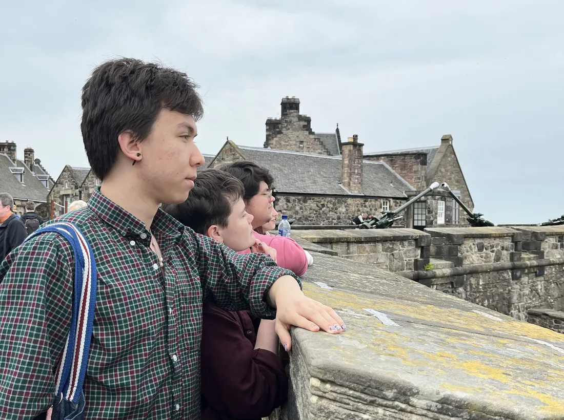 Three students look out over a wall in the United Kingdom.