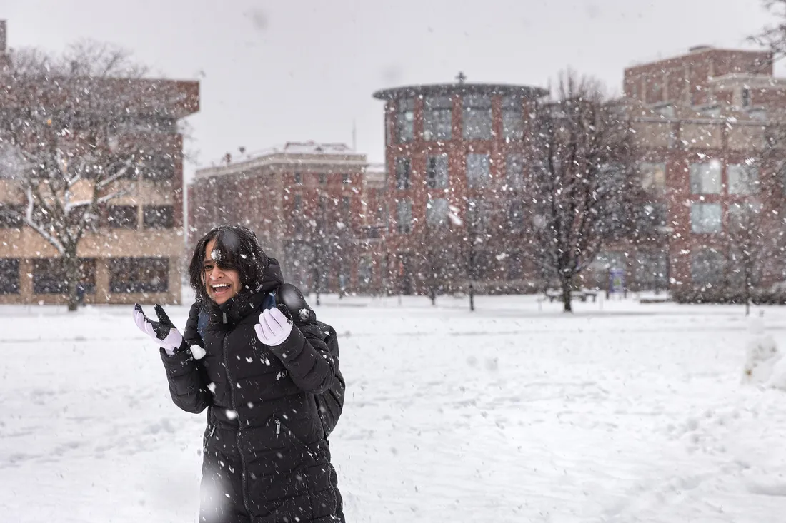 A student walks on campus while it snows.