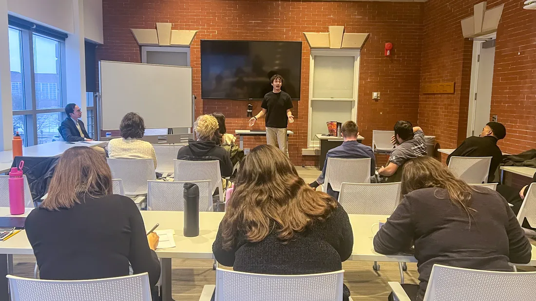 A student speaks in front of a room of people.