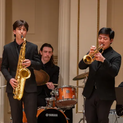 Three individuals perform on stage.