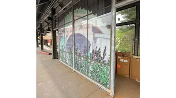 A large and colorful glass mural in a frame at a subway stop.