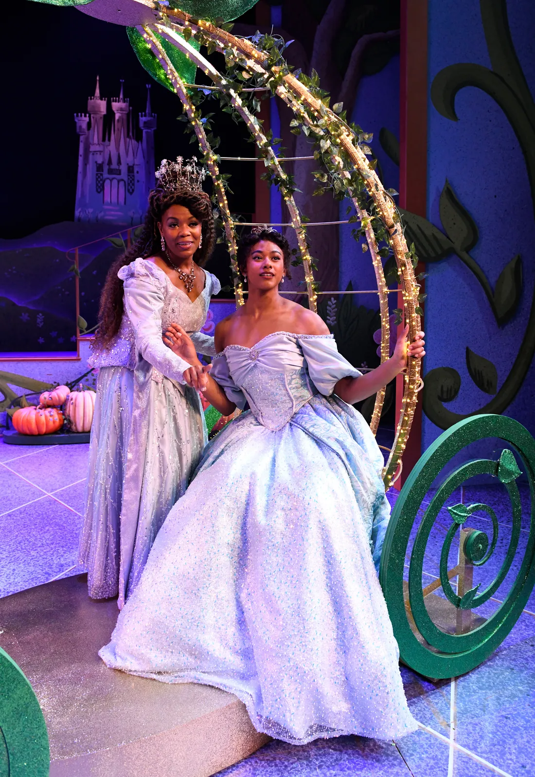 Two actors in gowns on a stage.