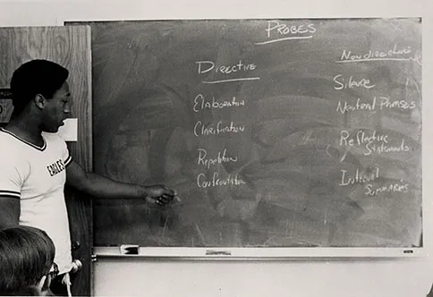 A student points to a blackboard in a class.
