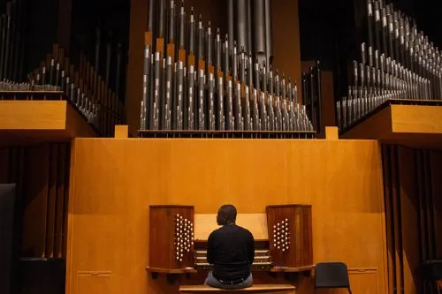 A person sits at the organ in Setnor Auditorium.