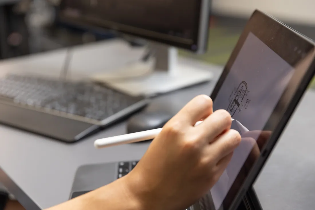 A hand draws on a tablet.