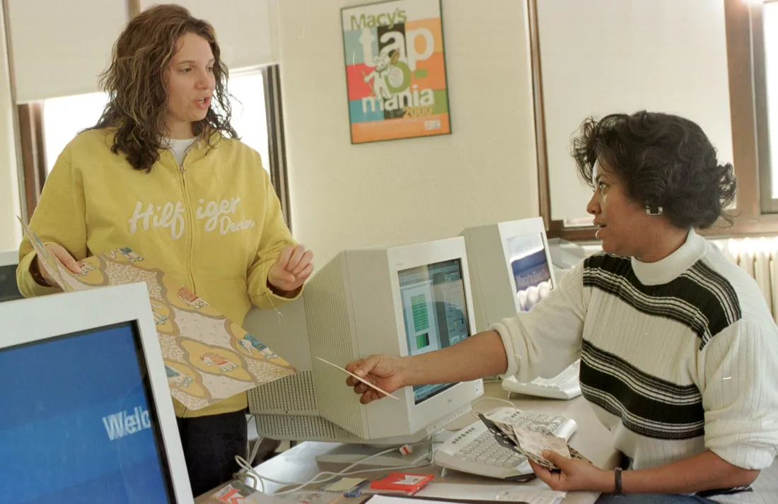 A student and teacher talk to each other in a computer studio.