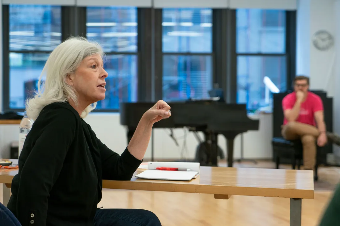A faculty member sits at a table and talks to a student who is not in the photo frame.
