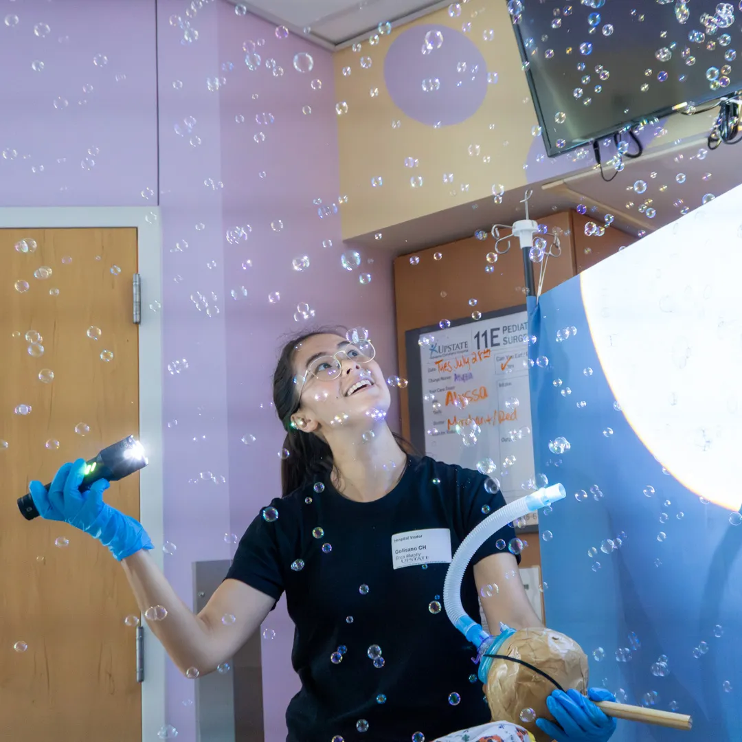 A person holds up a flashlight to illuminate bubbles in a hospital room.