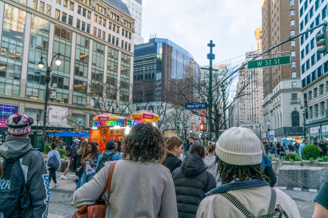 A group of people walk down a busy street in New York City.