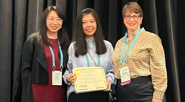 Li "Lily" Jiang poses with two other people and holds an award certificate.