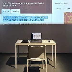 A table with a computer in front of a projected image.