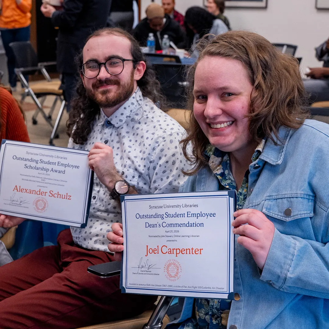 Two students hold awards certificates.