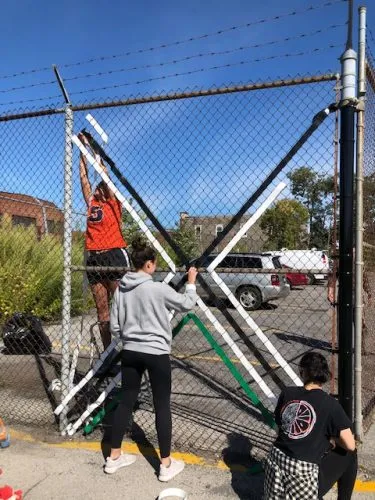 Students work on a project at a fence.