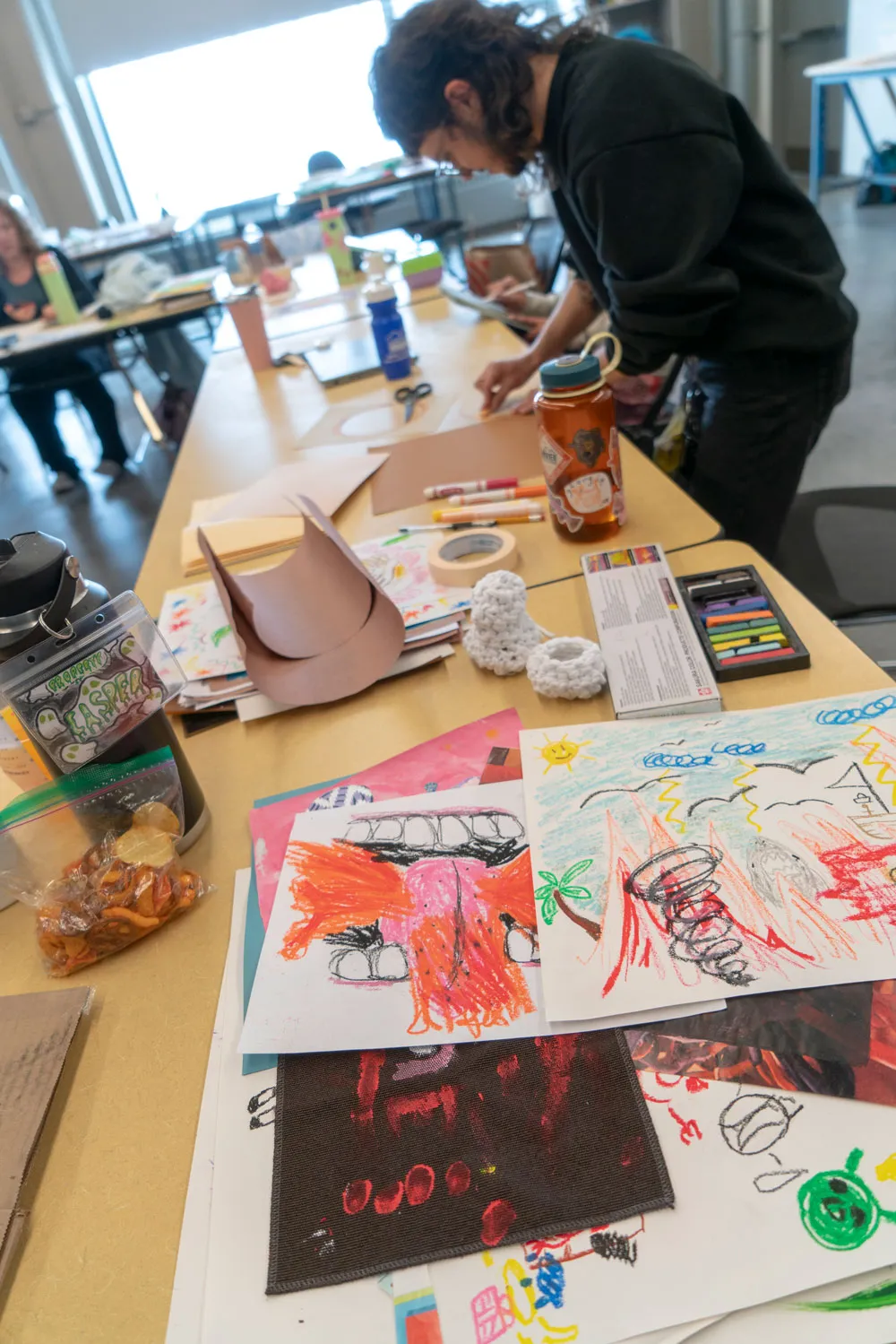 A student stands in front of a table creating a piece of art with paper.