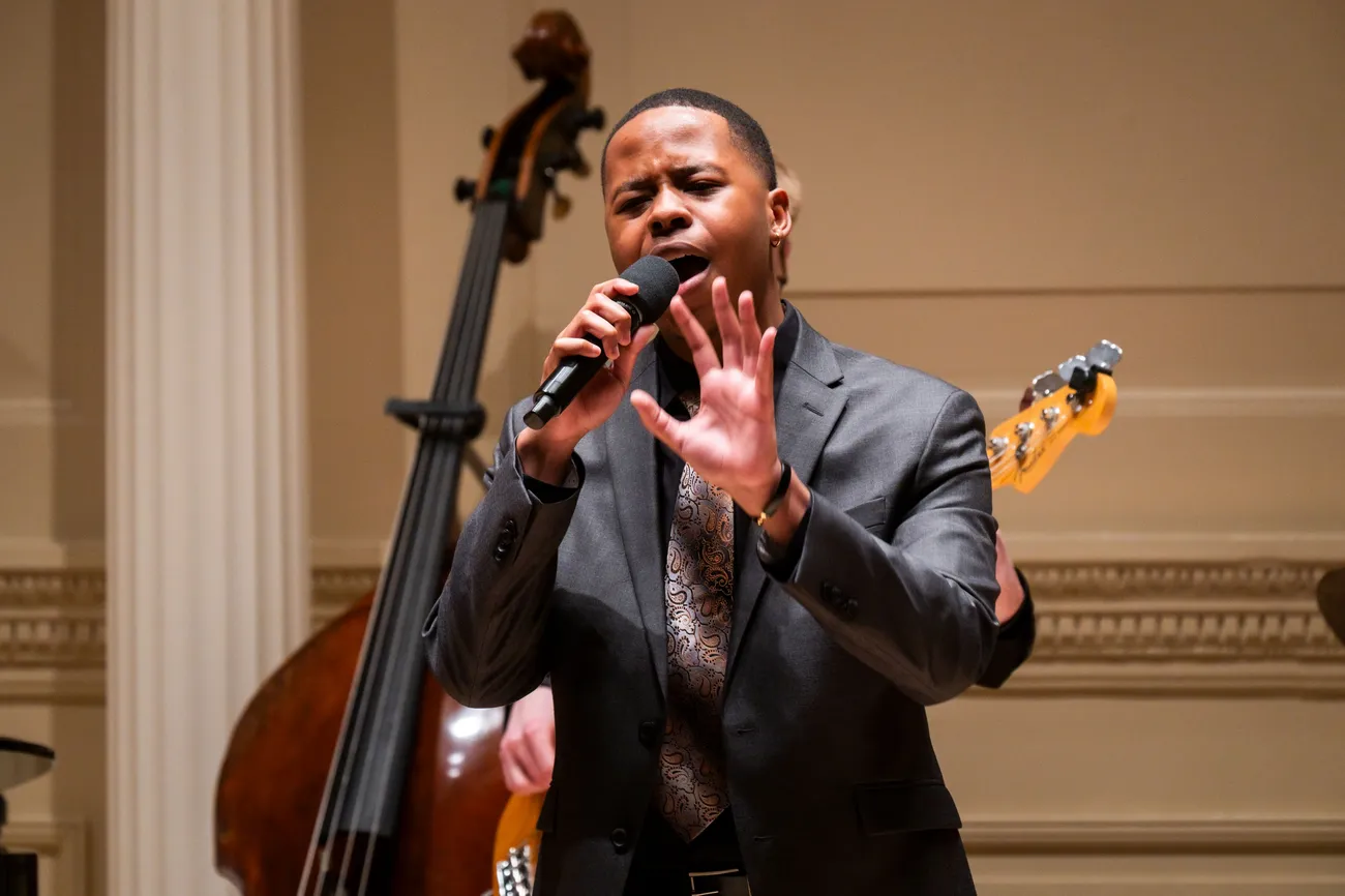 A singer performs in formal attire on stage.