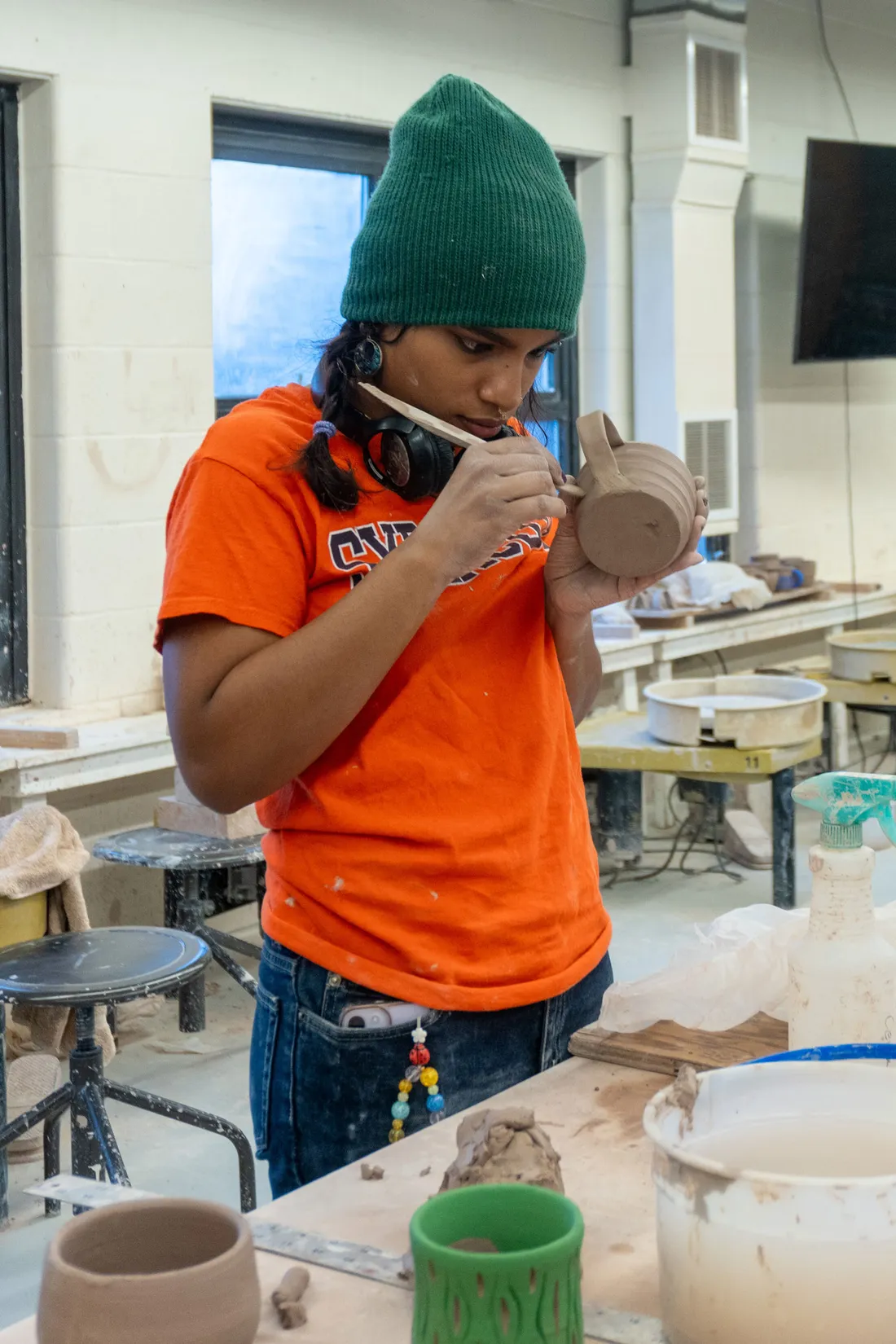 A student works on a clay cup in a ceramics studio.