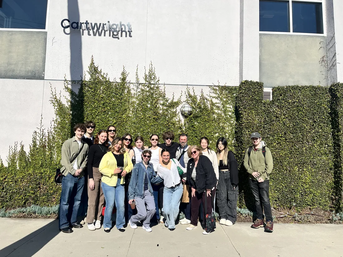 A group of people pose and smile outside a building with the sign Cartwright.