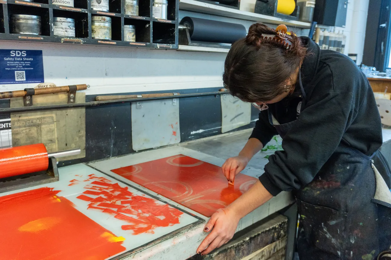 A student creates a print in a printmaking studio.