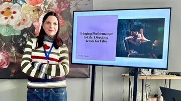 Sandy Siquier stands next to a screen showing a presentation.
