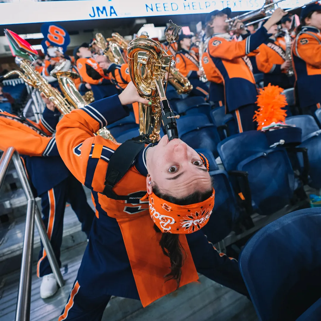 A person bends over while playing the saxophone.