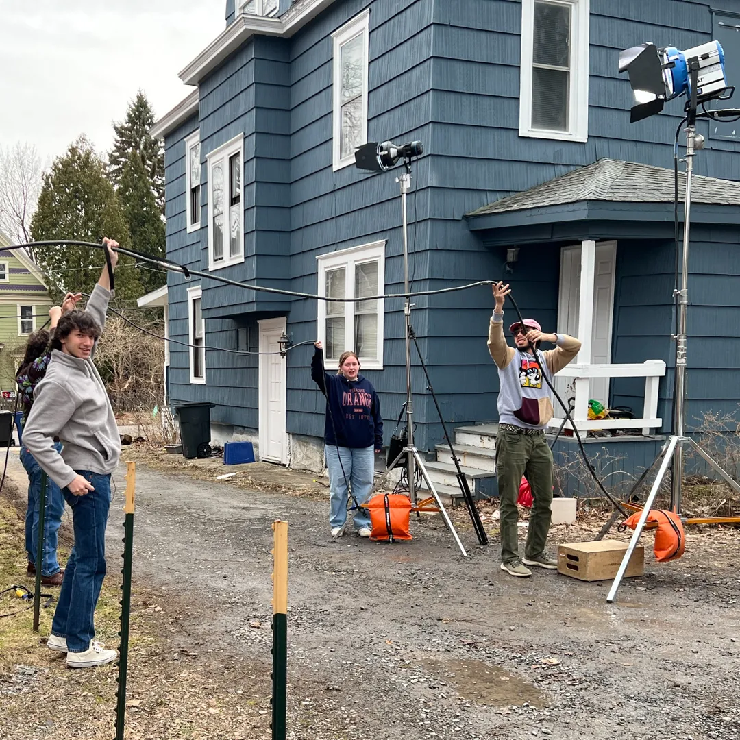Four students hold up cables outside on a film set.