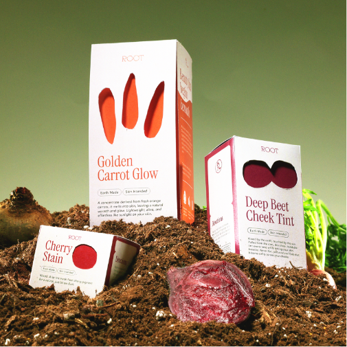 Natural-inspired cosmetic products from the brand “ROOT” are displayed in rich soil with fresh vegetables, including carrots and beets. The packaging highlights products such as “Golden Carrot Glow,” “Deep Beet Cheek Tint,” and “Cherry Stain,” creating an earthy, organic beauty aesthetic.