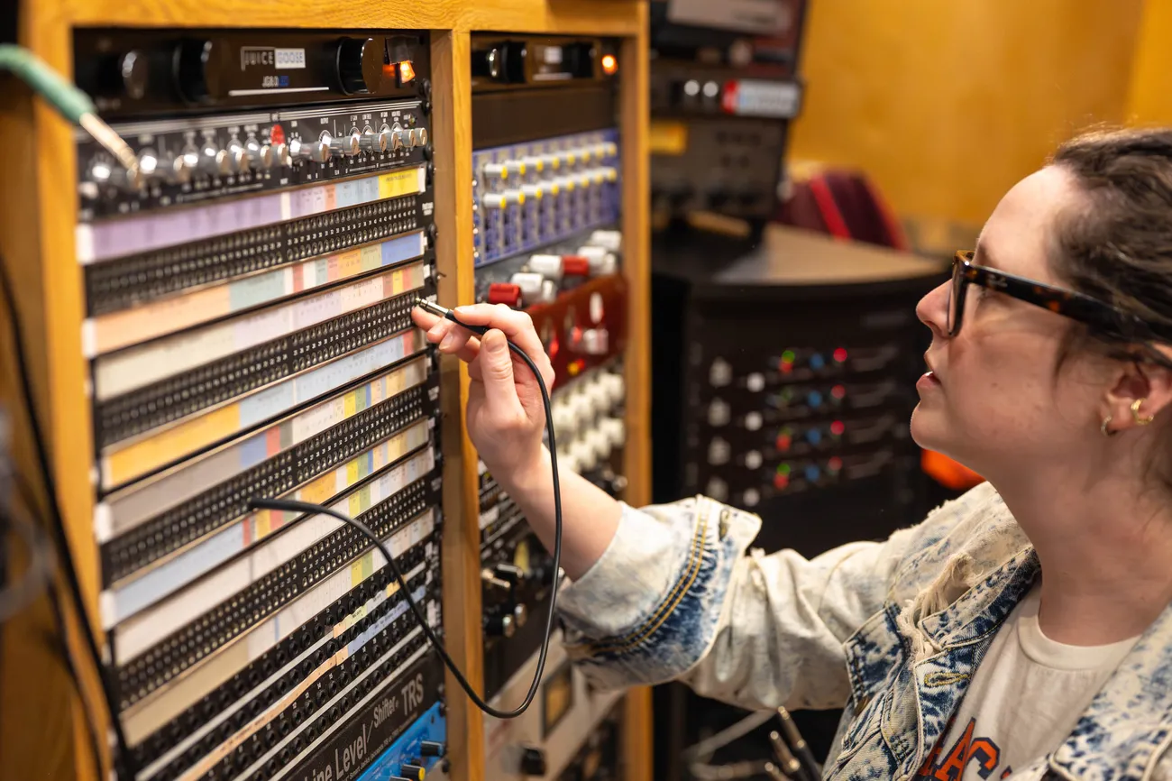 A person works at a piece of recording equipment in a music studio.